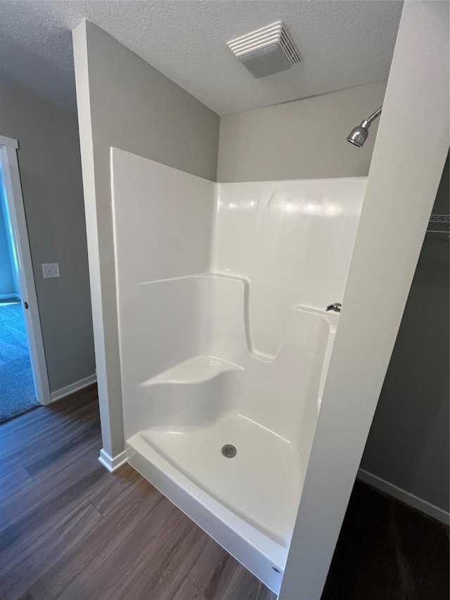 bathroom with hardwood / wood-style flooring, a shower, and a textured ceiling