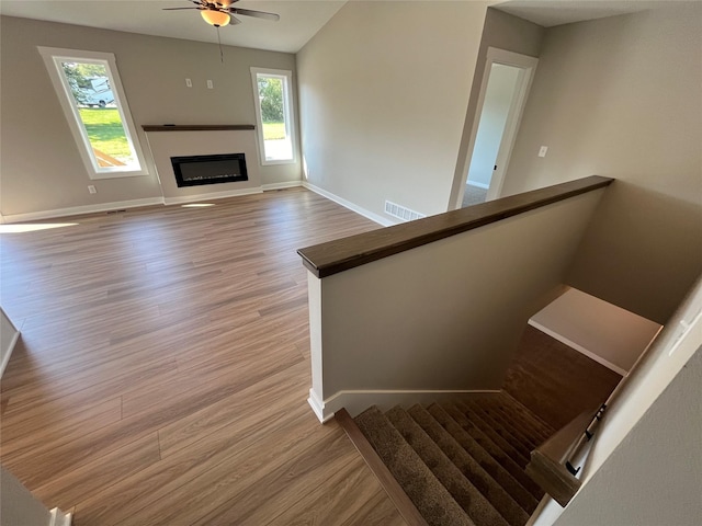 staircase with ceiling fan, lofted ceiling, and wood-type flooring