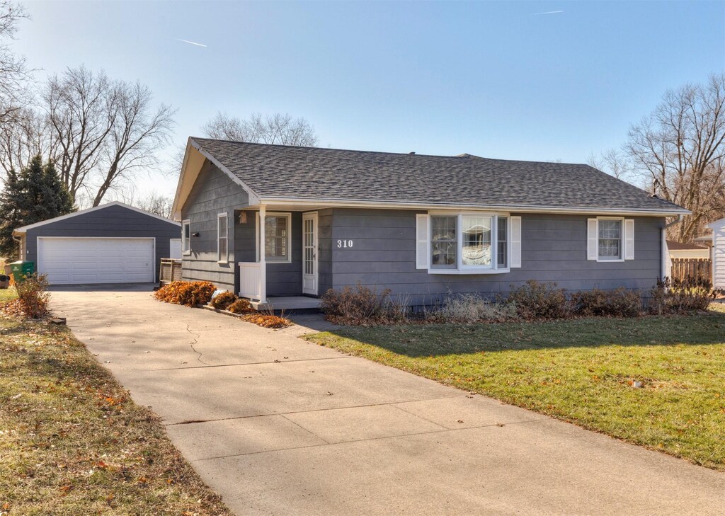 ranch-style house with a garage, an outbuilding, and a front lawn