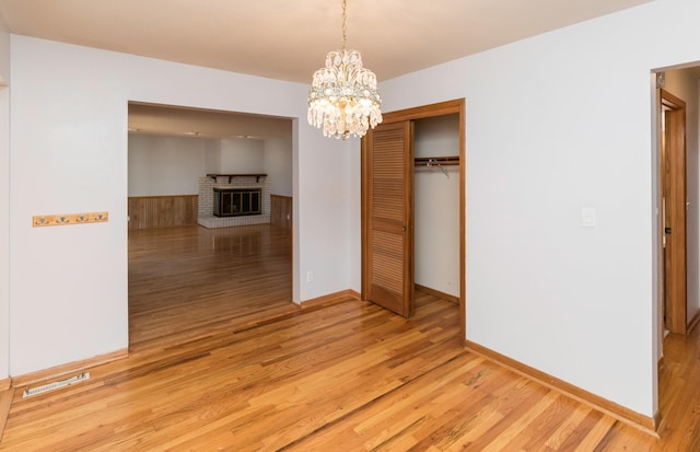 unfurnished dining area with light hardwood / wood-style floors, a fireplace, and a chandelier