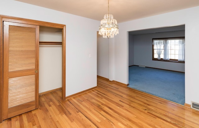 unfurnished dining area featuring light wood-type flooring and a chandelier