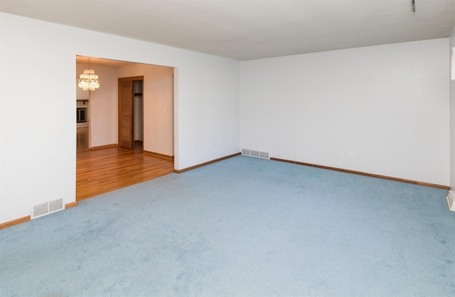 spare room with wood-type flooring and an inviting chandelier