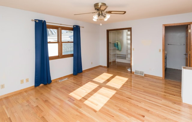 empty room with ceiling fan and light hardwood / wood-style flooring