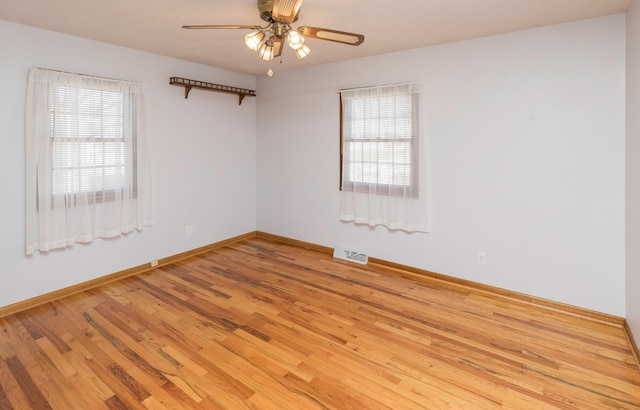 empty room featuring ceiling fan, plenty of natural light, and light wood-type flooring