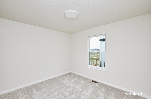 carpeted spare room featuring a textured ceiling