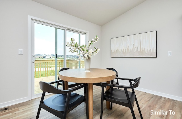 dining room featuring light hardwood / wood-style floors and vaulted ceiling