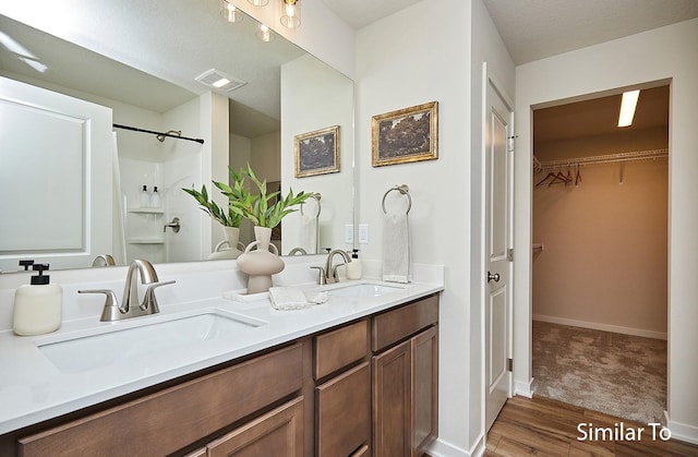 bathroom with walk in shower, vanity, and hardwood / wood-style floors