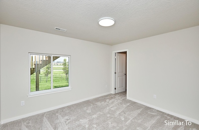 unfurnished room featuring light colored carpet and a textured ceiling