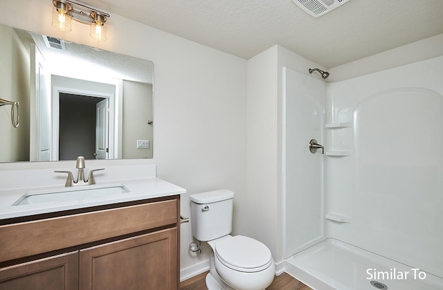 bathroom with walk in shower, vanity, toilet, and a textured ceiling