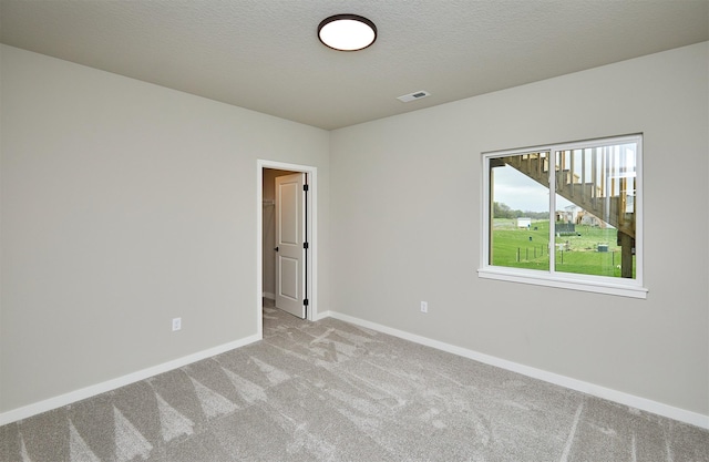 empty room featuring baseboards, visible vents, and light colored carpet