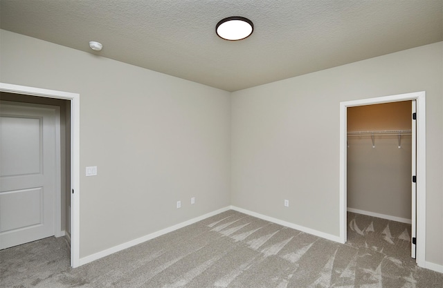 unfurnished bedroom with carpet flooring, baseboards, a spacious closet, and a closet