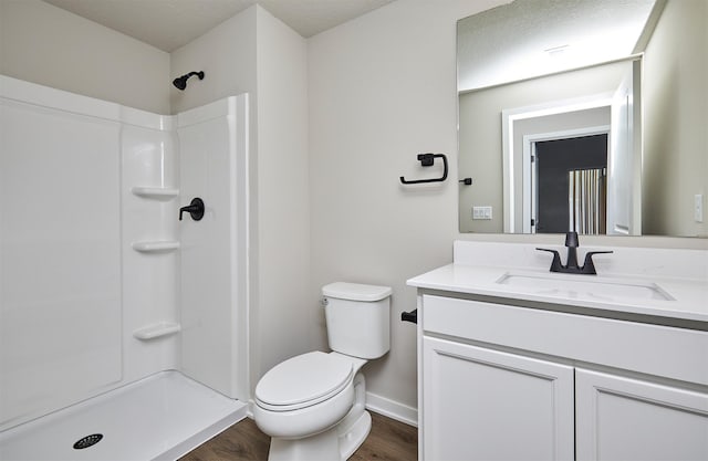 bathroom featuring toilet, walk in shower, wood finished floors, and vanity