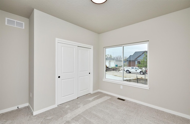 unfurnished bedroom with visible vents, a closet, and light carpet