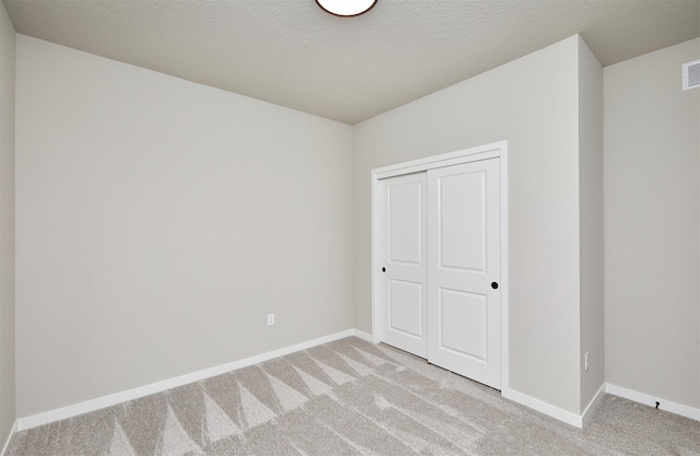 unfurnished bedroom featuring baseboards, a closet, visible vents, and light carpet