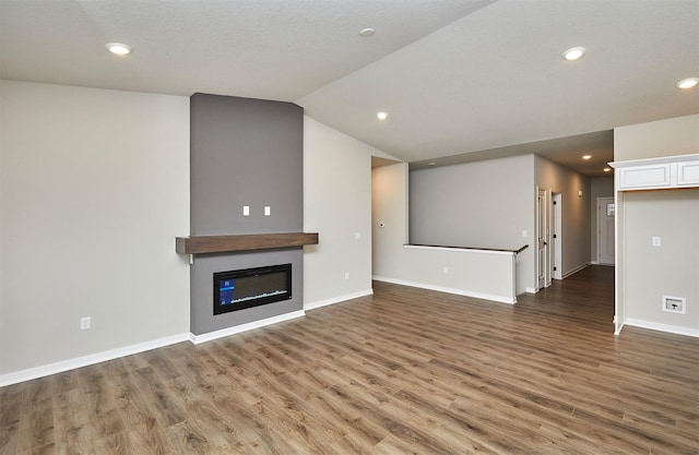 1064 NE 64th Ave, Des Moines, IA 50313 - unfurnished living room featuring a glass covered fireplace, wood finished floors, lofted ceiling, baseboards, and recessed lighting