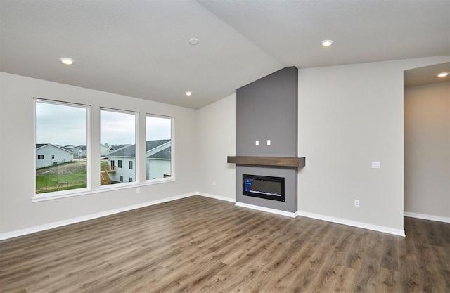 unfurnished living room with a glass covered fireplace, wood finished floors, baseboards, recessed lighting, and vaulted ceiling