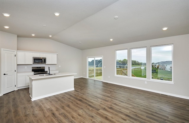 kitchen featuring an island with sink, appliances with stainless steel finishes, tasteful backsplash, vaulted ceiling, and dark wood-type flooring