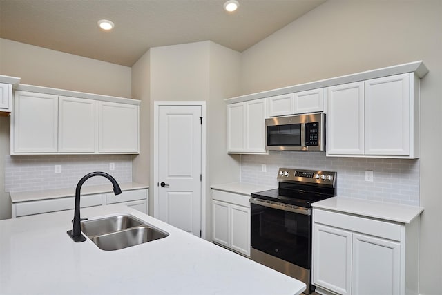 kitchen with white cabinets, a sink, light countertops, stainless steel appliances, and backsplash