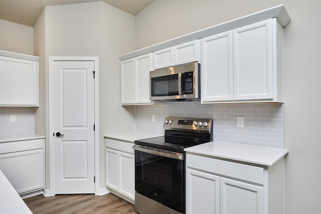 kitchen with backsplash, stainless steel appliances, light wood-style flooring, and light countertops