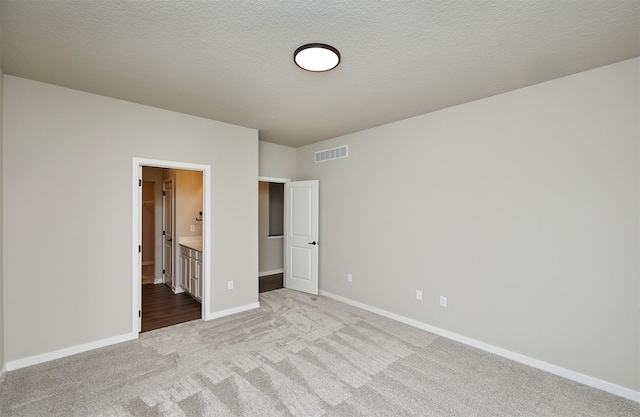 unfurnished bedroom featuring connected bathroom, light colored carpet, baseboards, and visible vents