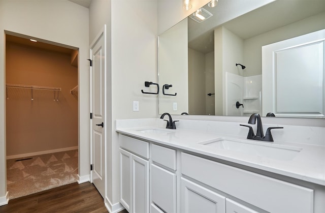 bathroom with wood finished floors, visible vents, a sink, and a shower