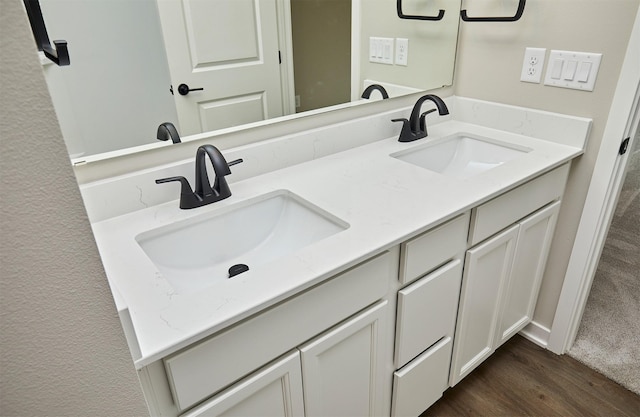 bathroom with double vanity, a sink, and wood finished floors