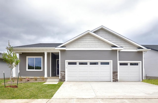 view of front facade featuring an attached garage, driveway, stone siding, and a front yard