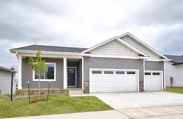 view of front of house featuring an attached garage, driveway, stone siding, and a front lawn