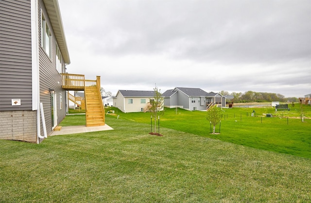 view of yard with a residential view, a wooden deck, and stairs