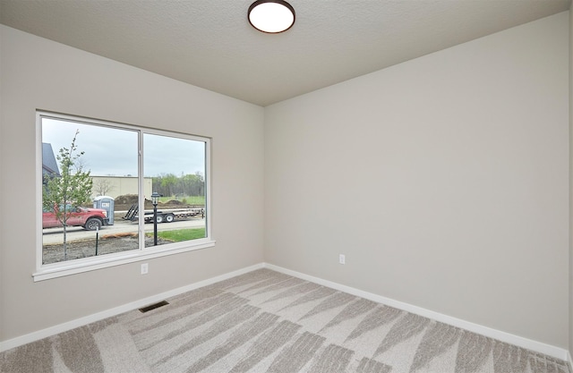 carpeted spare room with baseboards and visible vents