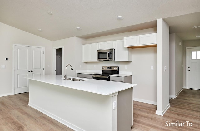 kitchen with white cabinetry, appliances with stainless steel finishes, sink, and an island with sink