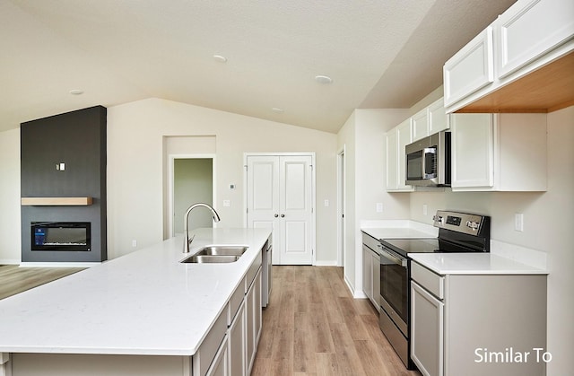 kitchen with stainless steel appliances, white cabinetry, sink, and a center island with sink