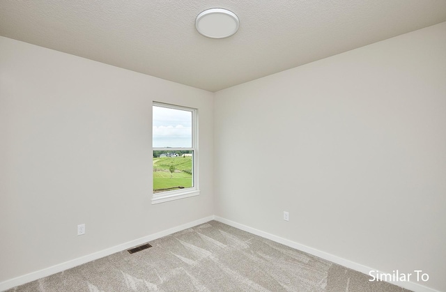 carpeted empty room featuring a textured ceiling