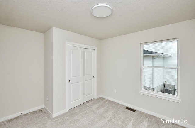 unfurnished bedroom with multiple windows, light colored carpet, and a closet