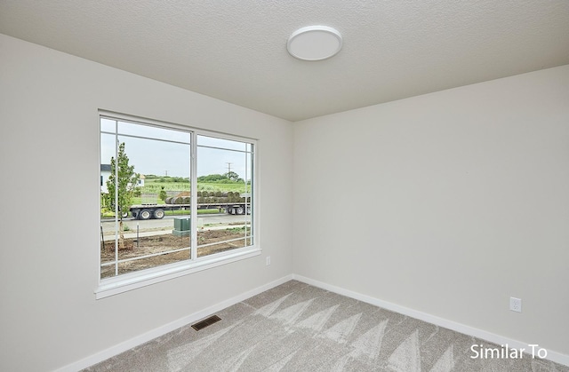 carpeted empty room featuring a textured ceiling