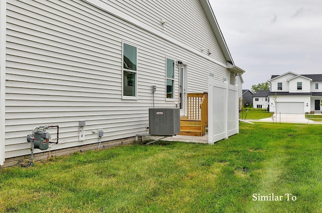 view of property exterior with a lawn, central AC unit, and a garage