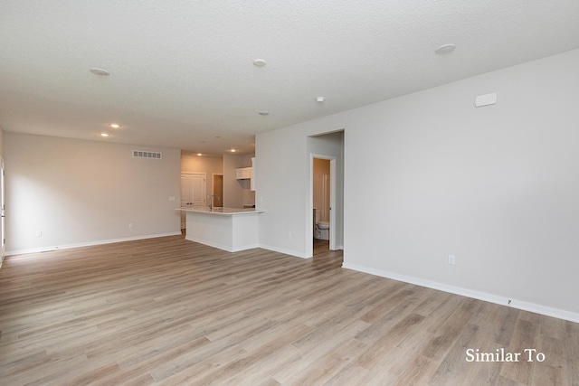 unfurnished living room with a textured ceiling and light wood-type flooring