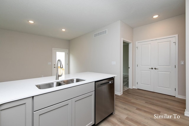 kitchen featuring gray cabinetry, dishwasher, sink, a textured ceiling, and light wood-type flooring