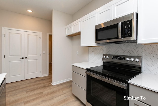 kitchen featuring decorative backsplash, white cabinetry, stainless steel appliances, and light hardwood / wood-style floors