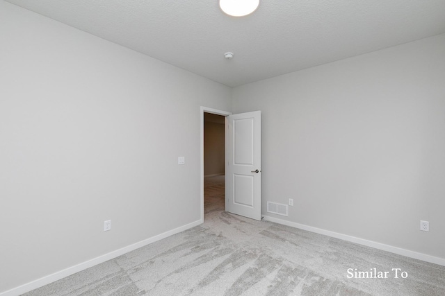 spare room featuring light carpet and a textured ceiling