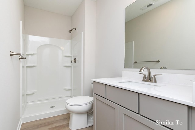 bathroom with a shower, toilet, vanity, and hardwood / wood-style flooring