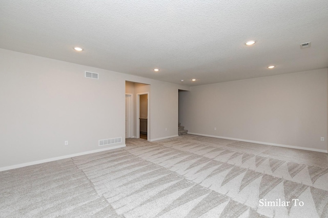 unfurnished room featuring light carpet and a textured ceiling