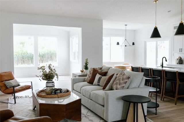 living room with sink, a notable chandelier, and light wood-type flooring