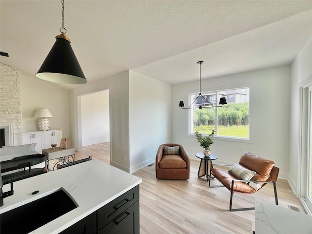 kitchen with pendant lighting, lofted ceiling, light wood-type flooring, a fireplace, and a notable chandelier