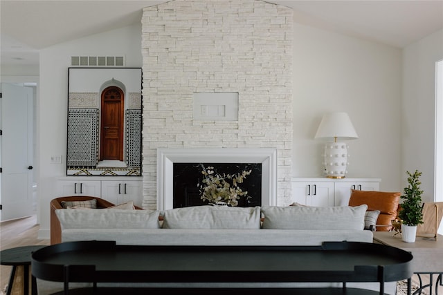 living room featuring a fireplace, hardwood / wood-style floors, and vaulted ceiling