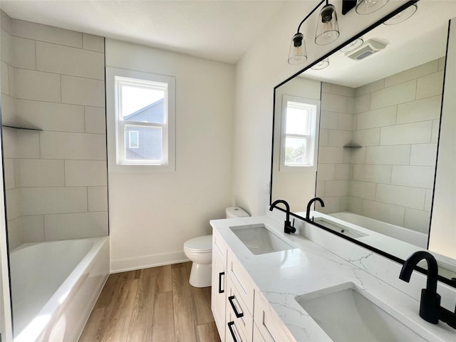 full bathroom featuring a wealth of natural light, hardwood / wood-style floors, vanity, and toilet