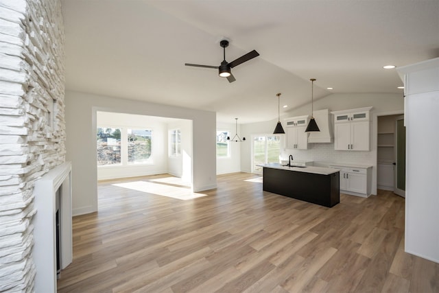 kitchen with white cabinetry, an island with sink, a healthy amount of sunlight, and custom exhaust hood