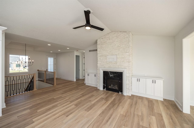 unfurnished living room featuring a fireplace, ceiling fan with notable chandelier, vaulted ceiling, and light wood-type flooring