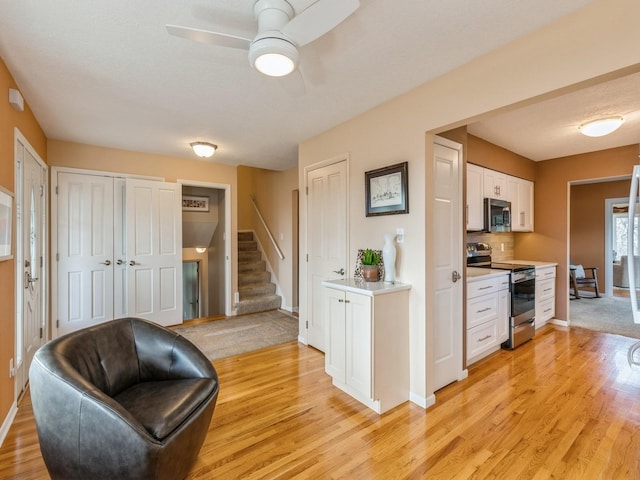 kitchen with ceiling fan, white cabinetry, stainless steel appliances, light hardwood / wood-style floors, and decorative backsplash