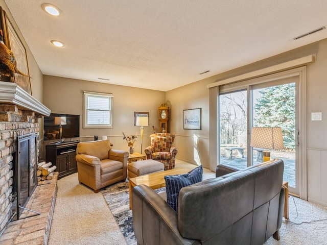 living room featuring a brick fireplace, light carpet, and a textured ceiling